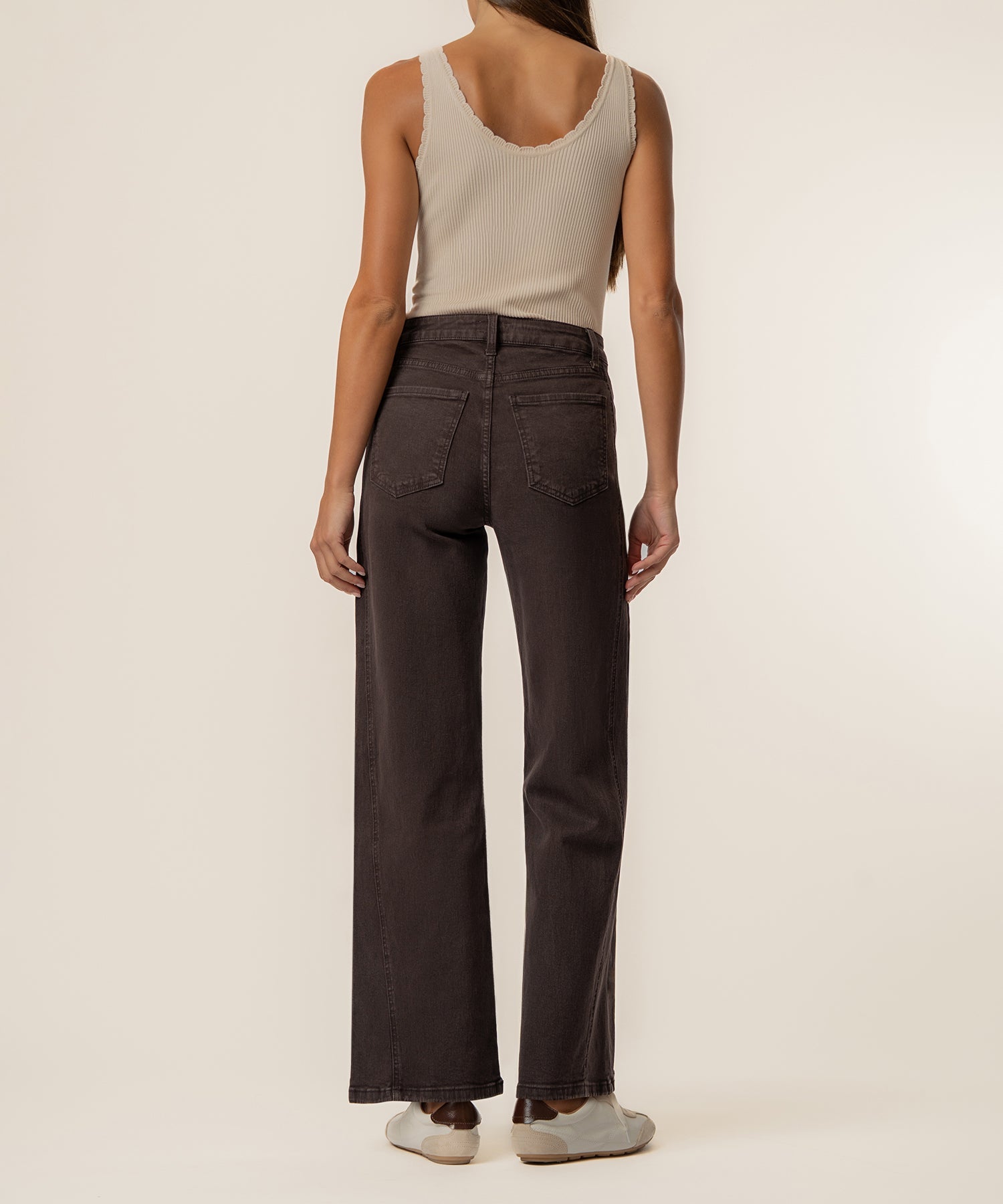 Woman wearing chocolate brown high-rise wide-leg jeans with cream ribbed tank top, rear view.