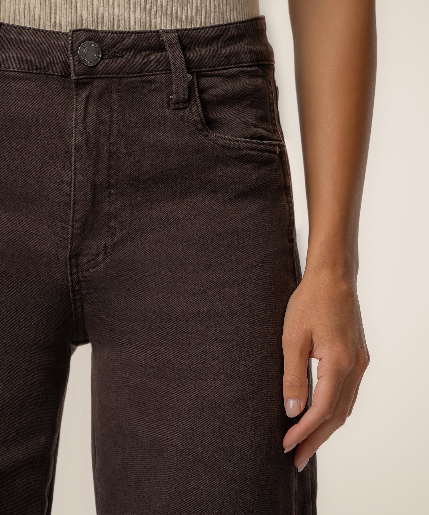 Chocolate brown high-rise wide-leg jeans with button closure and five-pocket styling on model.