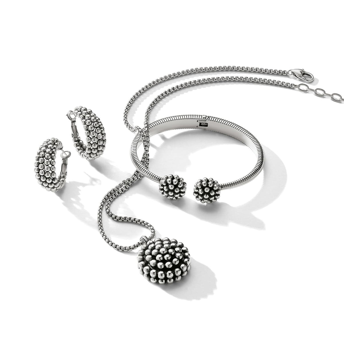 Brighton silver-plated jewelry set styled with beaded pendant necklace, hoop earrings, and cuff bracelet on white background