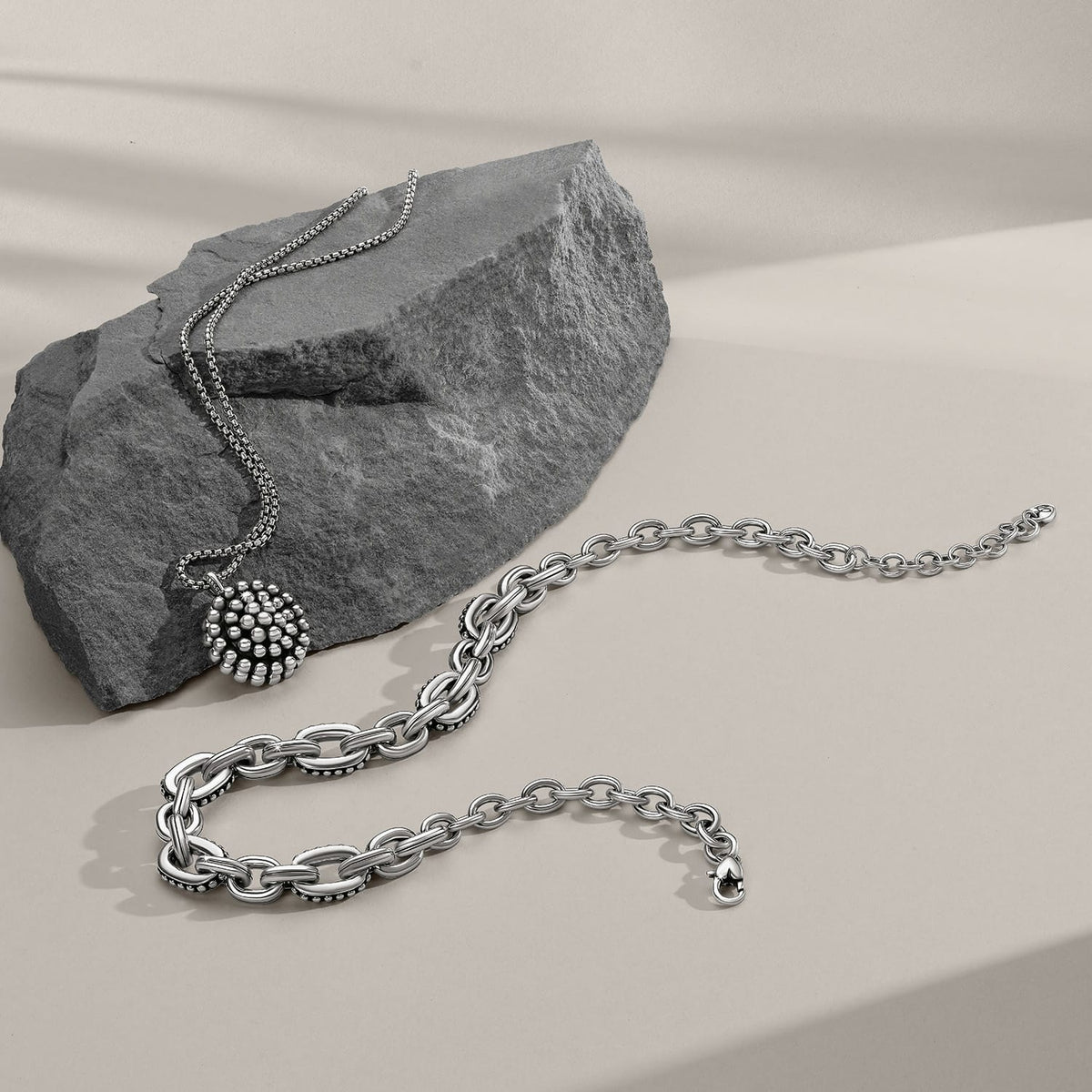 Brighton silver-plated jewelry styled with a stone slab, featuring a beaded pendant necklace and chain link bracelet