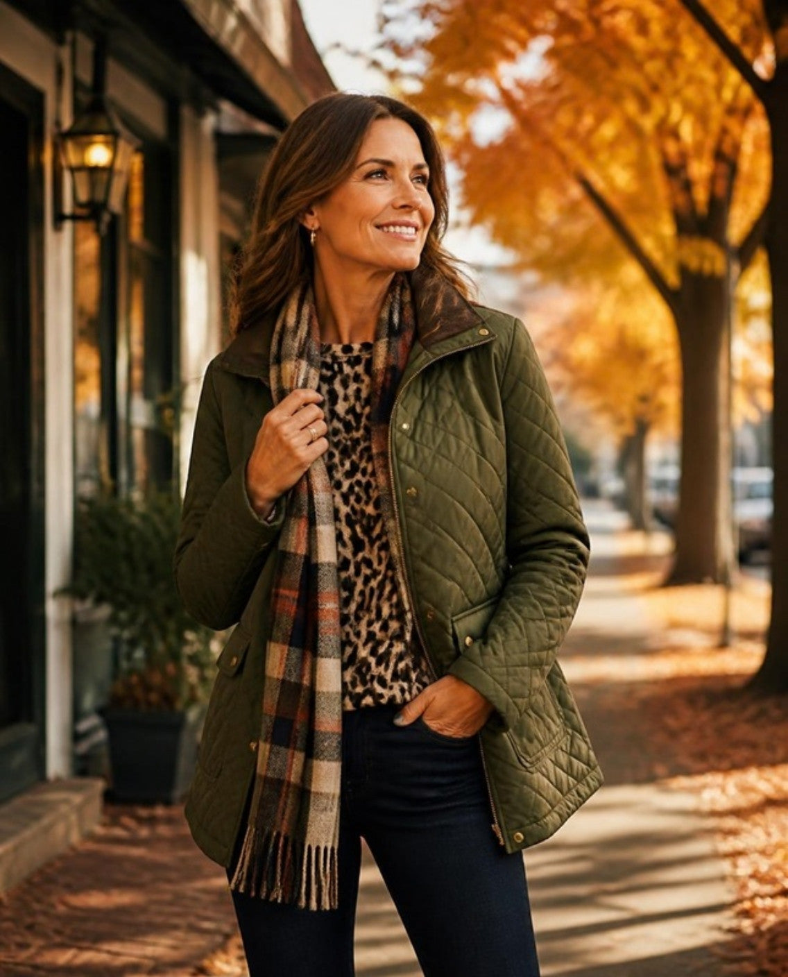 Woman in an olive quilted jacket, leopard top and plaid scarf on an autumn street