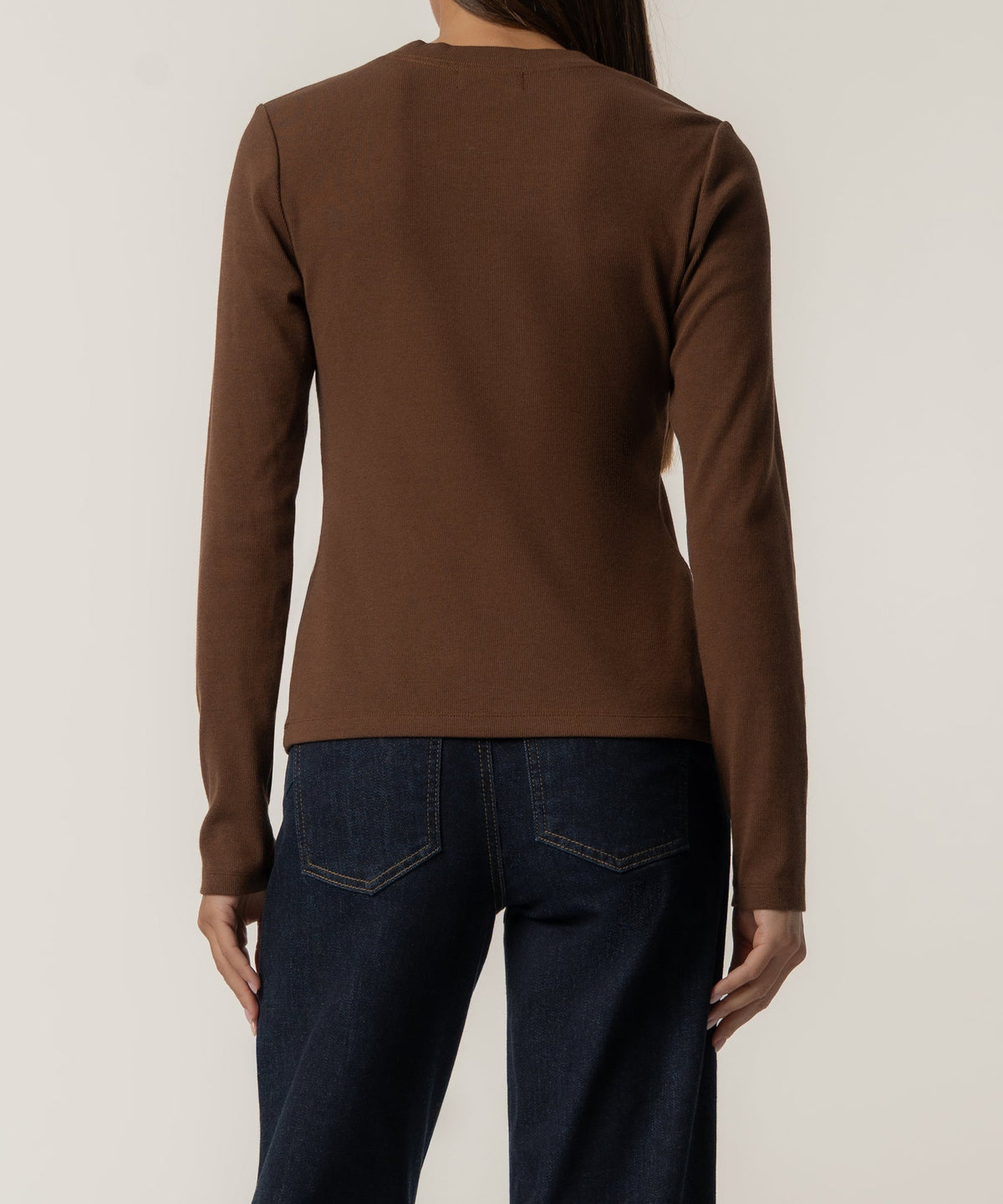 Chocolate brown long-sleeve knit top worn with dark denim jeans, back view.