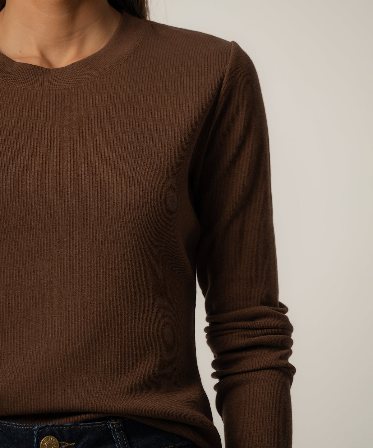 Chocolate brown ribbed knit top with crew neckline and long sleeves on model.
