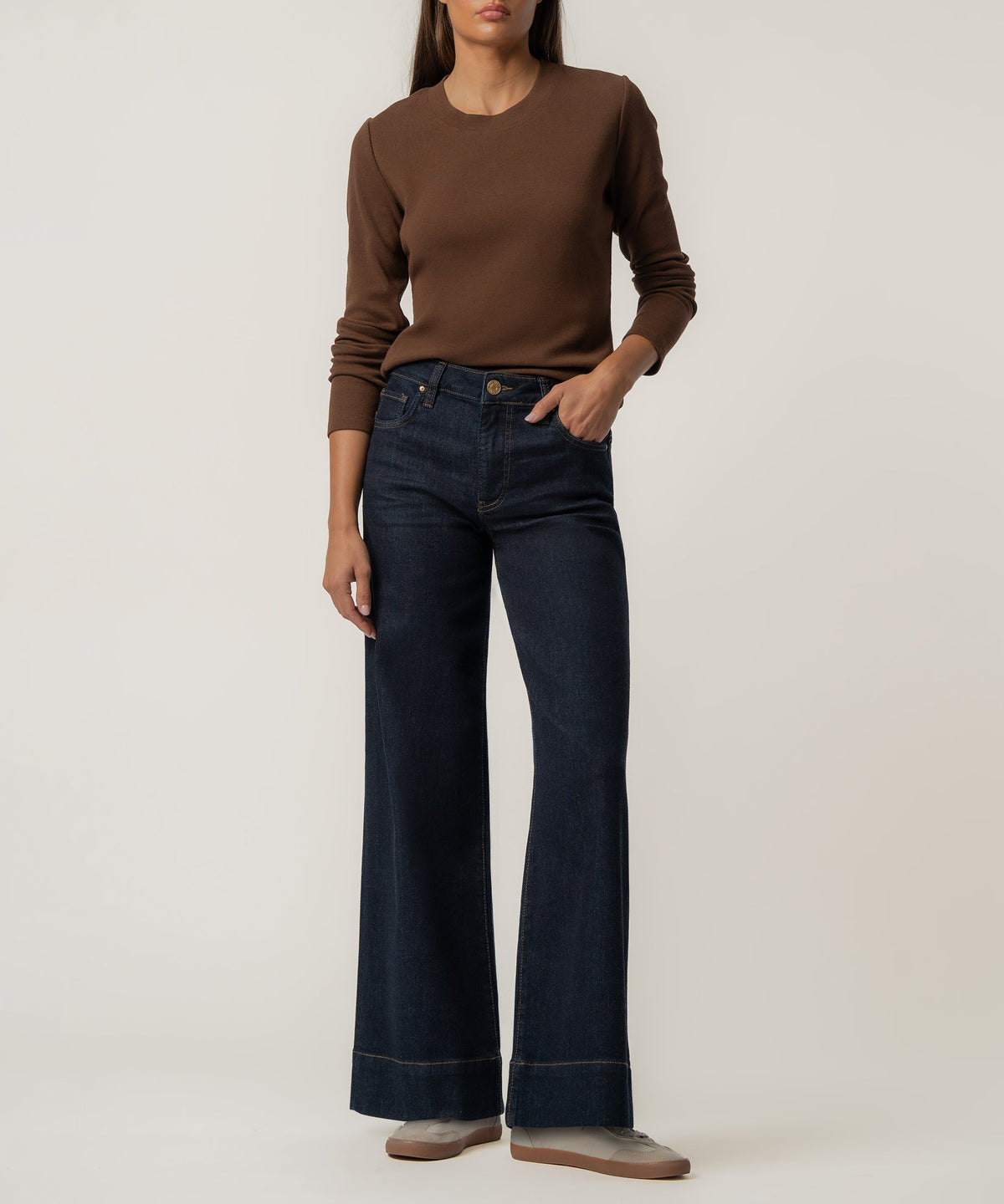 Woman wearing a brown long-sleeve knit top with dark blue wide-leg jeans.