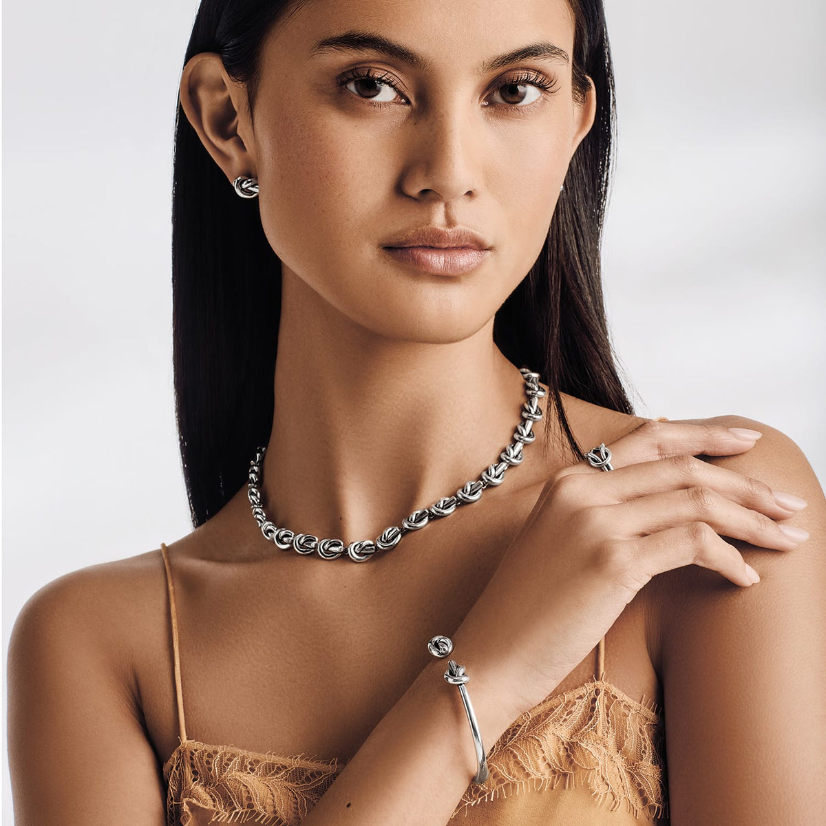 Model wearing a Brighton silver-plated knot-link necklace with coordinating Brighton earrings, ring, and cuff bracelet