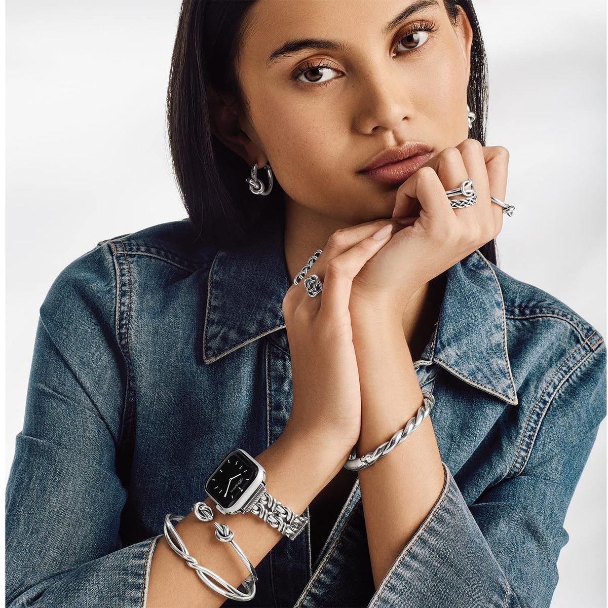 Model wearing a Brighton silver-plated watch with braided band and coordinating Brighton accessories including bangles, rings, and hoop earrings