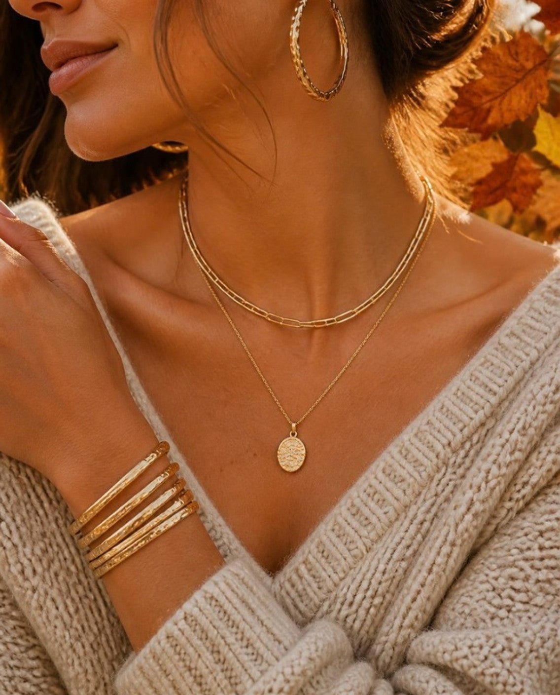 Layered gold necklaces, hoops and bangles with a chunky knit sweater