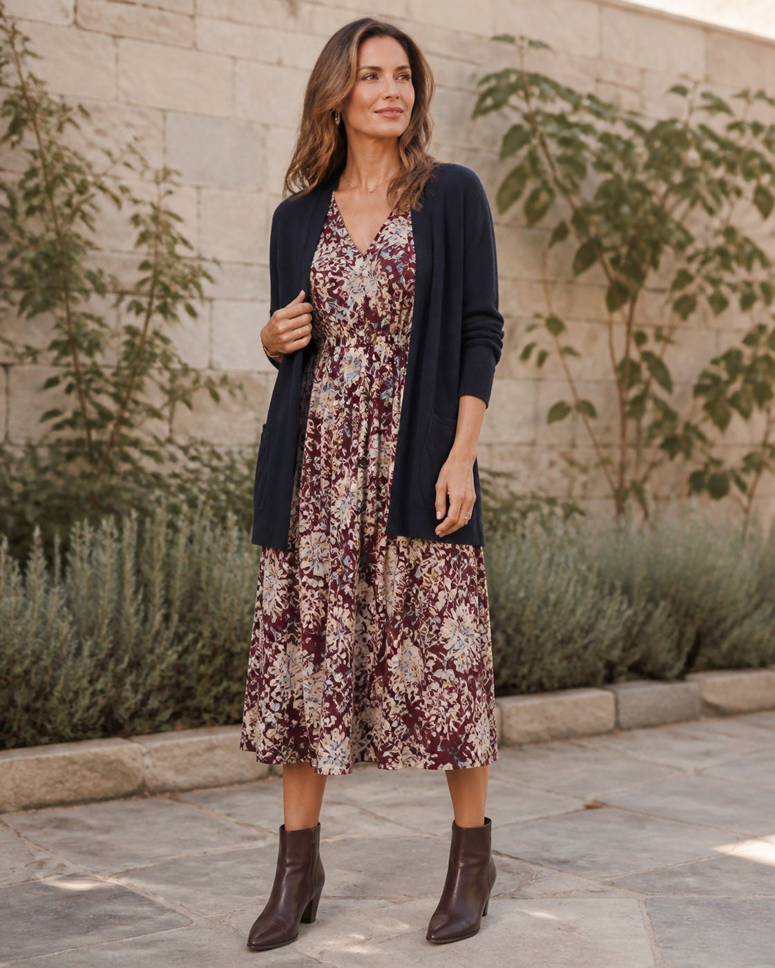 Woman wearing a burgundy, cream and blue botanical midi dress in a courtyard